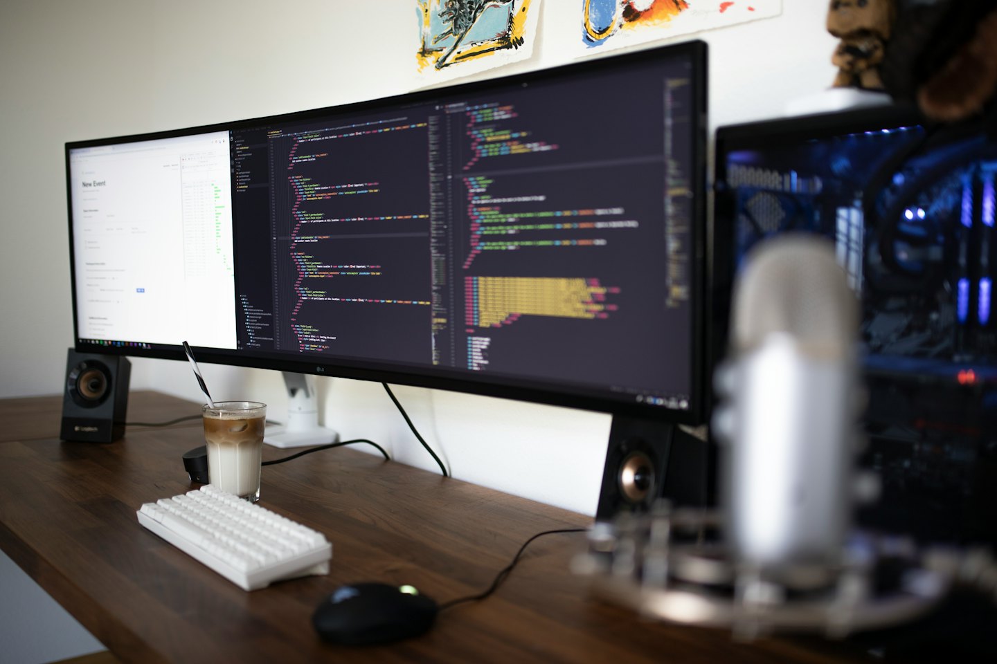 Bureau met ultrawide monitor, toetsenbord, muis en ijsthee.